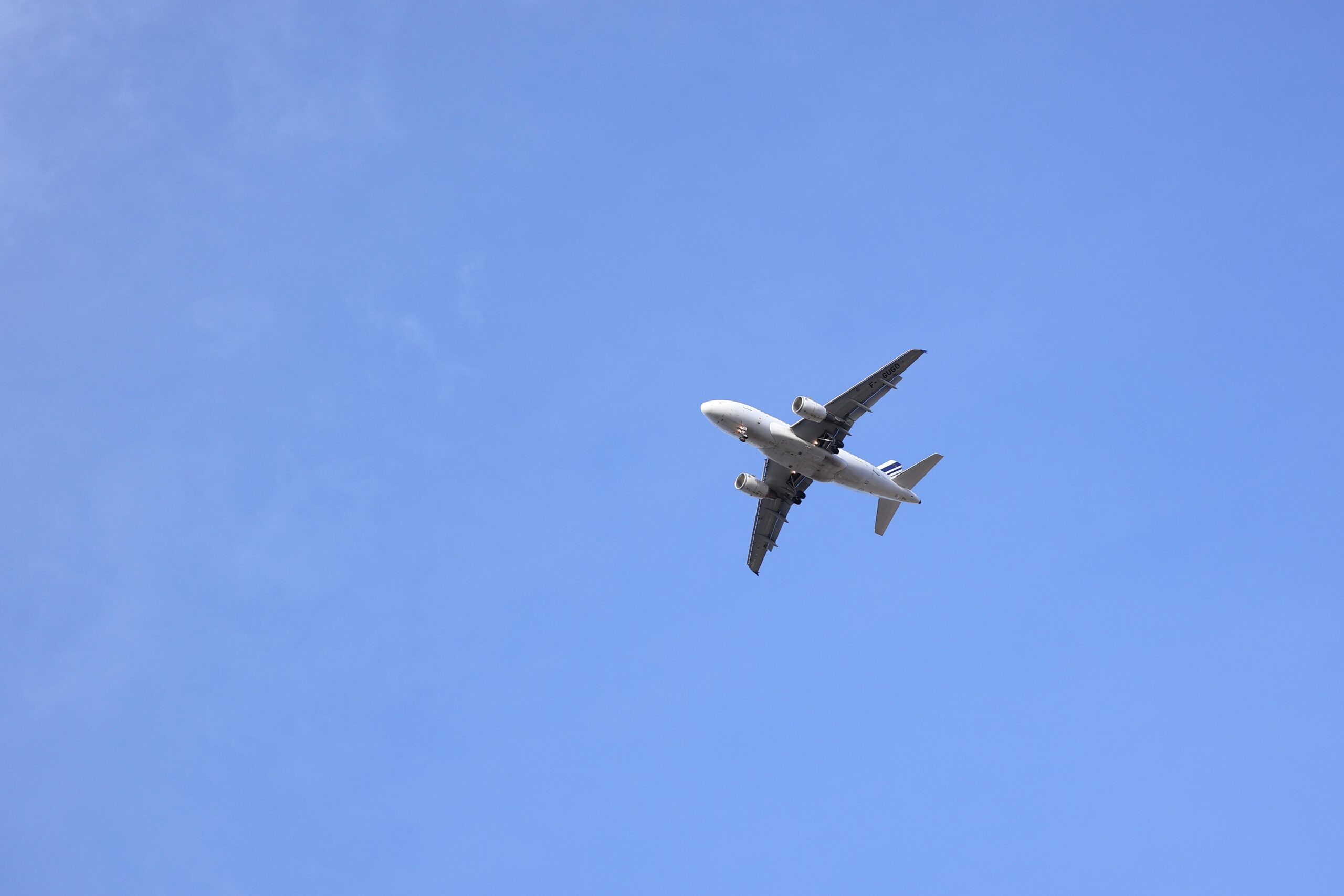 A commercial airplane flying high against a clear blue sky.